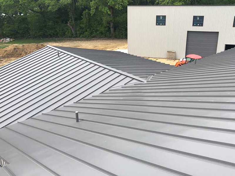 Close up of a gray metal roof being installed on a new construction commercial project