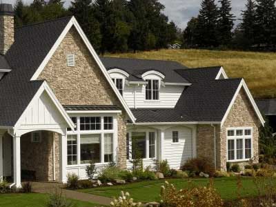 Front view of a large, higher-end home with black CertainTeed shingles on its roof