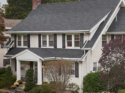 Front view of a typical mid-class home with dark gray GAF shingles on its roof