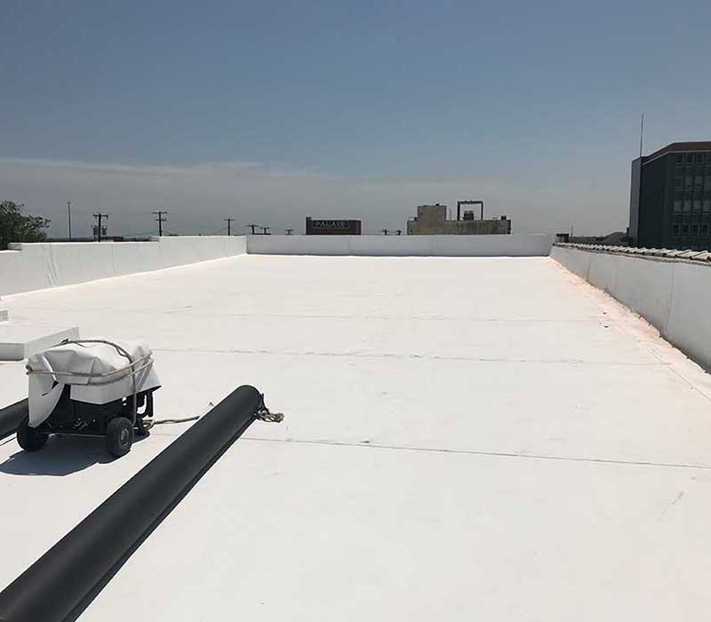 Overview of a flat commercial roof with a new white TPO system installed by Tejas Roofing & Gutters